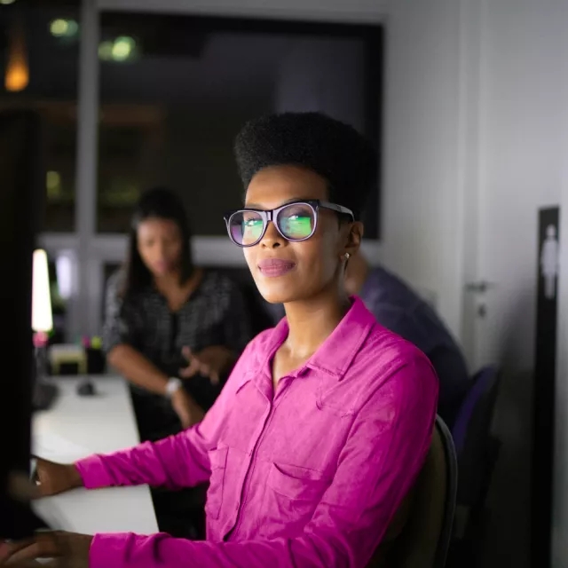 Woman working at computer smiling in pink shirt