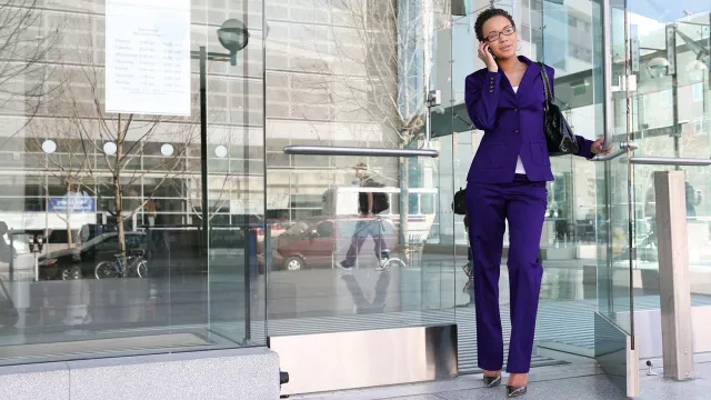 Image of woman on phone exiting a building