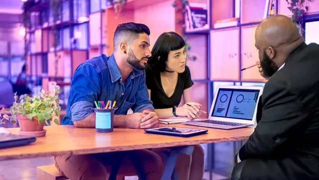 Image of team discussing graphs in a laptop