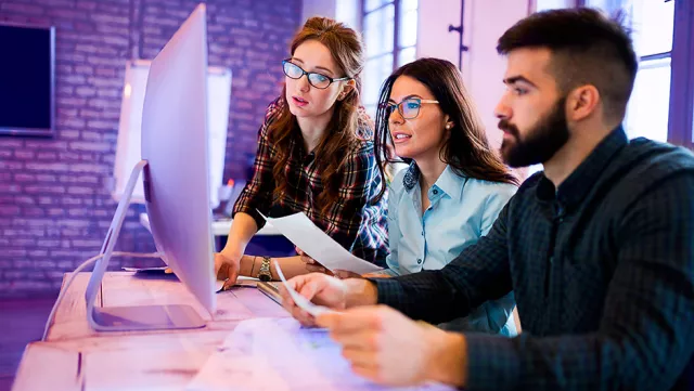 Image of team discussing in front of a computer