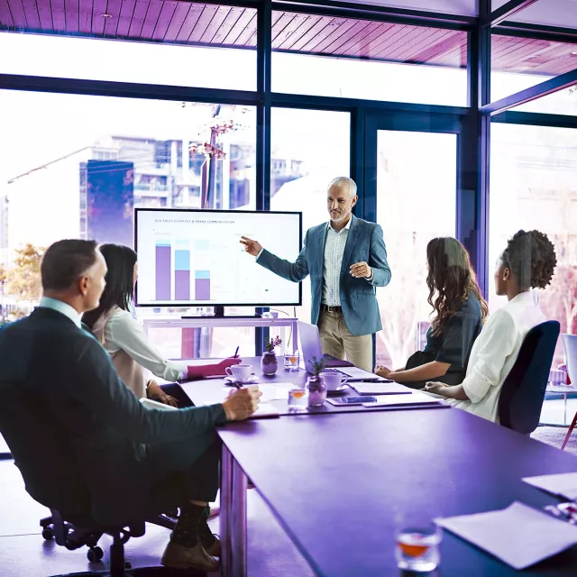 Image of team discussing bar graphs presentation in an office