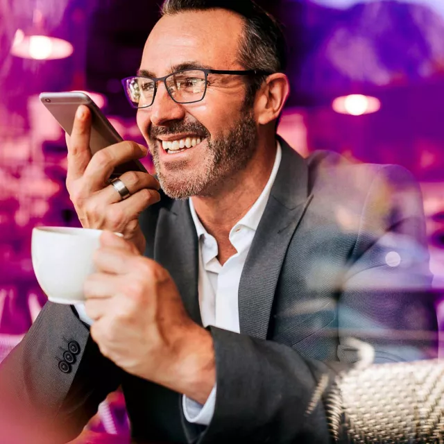 Image of man happily talking on mobile phone while holding cup