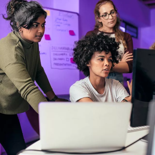 Image of three women discussing in front of a computer