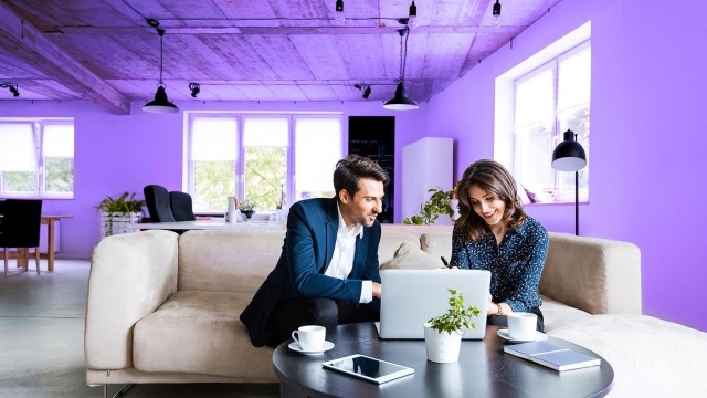 Image of officemates discussing on a couch in front of laptop