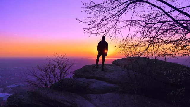 Image of a man standing near the edge of a cliff looking over the horizon