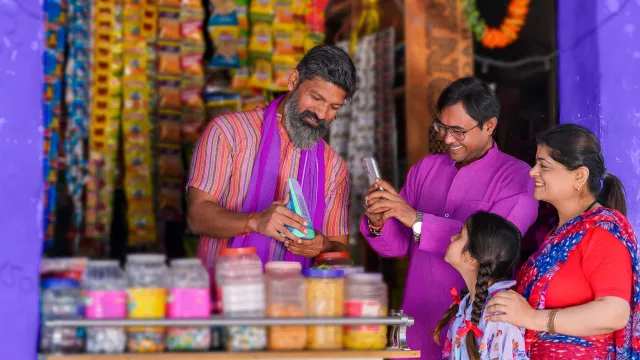 Image of 4 persons checking a QR code for payment at a local shop