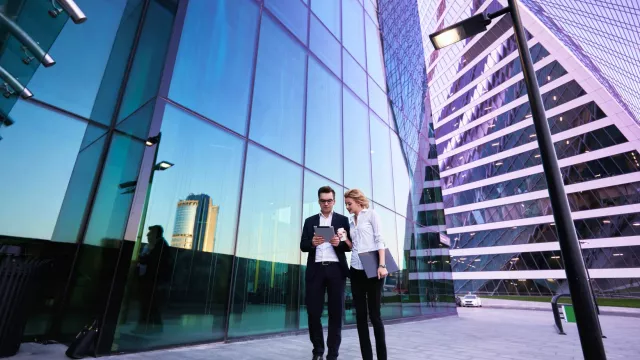 Image of two officemates outdoors in front of a glass building