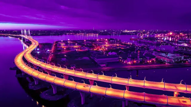 Stunning illuminated bridge at night with vibrant purple sky and city lights