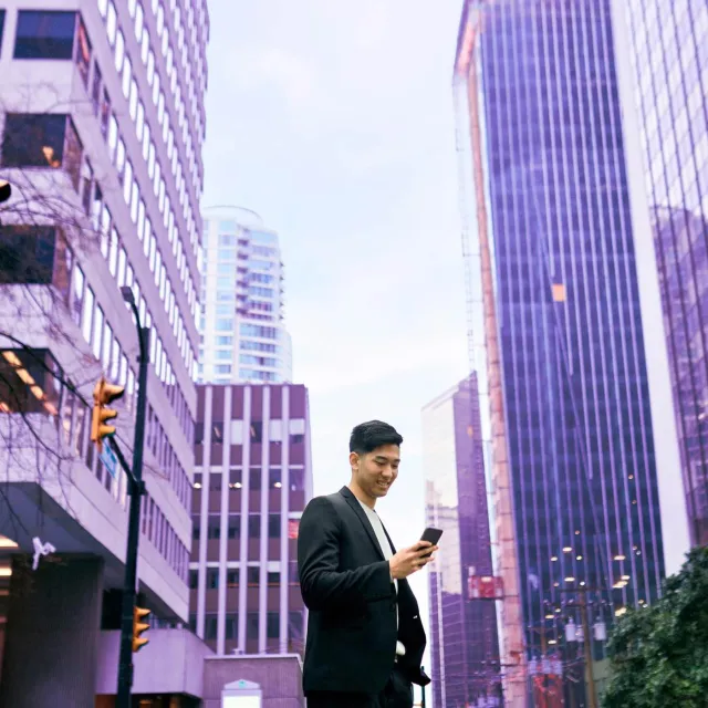 Image of man looking at phone in the middle of a city