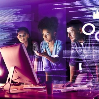 Image of three officemates discussing in front of a monitor