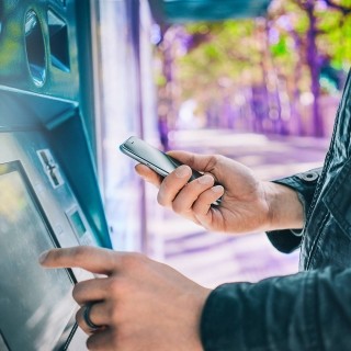 Image of person using mobile phone and ATM