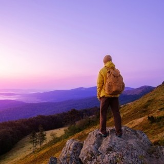Image of hiker on top of a rock formation looking over the horizon