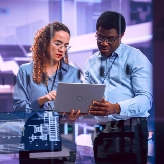 Image of officemates discussing while holding a laptop