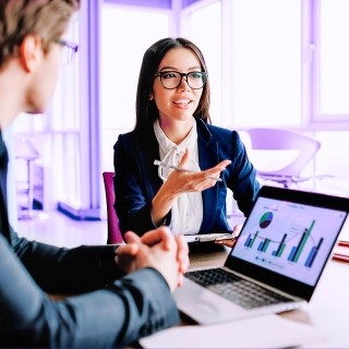 Business professionals discussing data analytics with charts on a laptop
