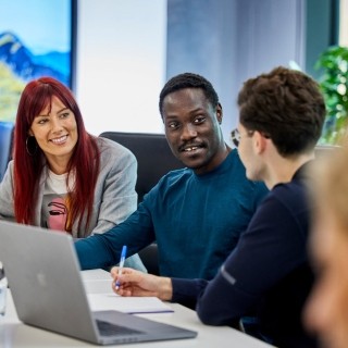 Image of three officemates discussing in an office