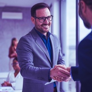 Image of man smiling toward and shaking hands with another man