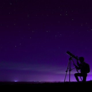 Image of person looking at the night sky through a telescope