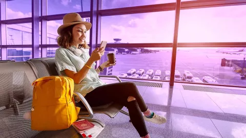 Image of woman in airport seating area looking at her mobile