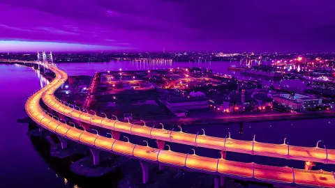 Stunning illuminated bridge at night with vibrant purple sky and city lights